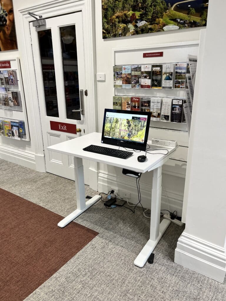 Adjustable height desk with a computer on it for visitors at the Beechworth Visitor Information Centre.